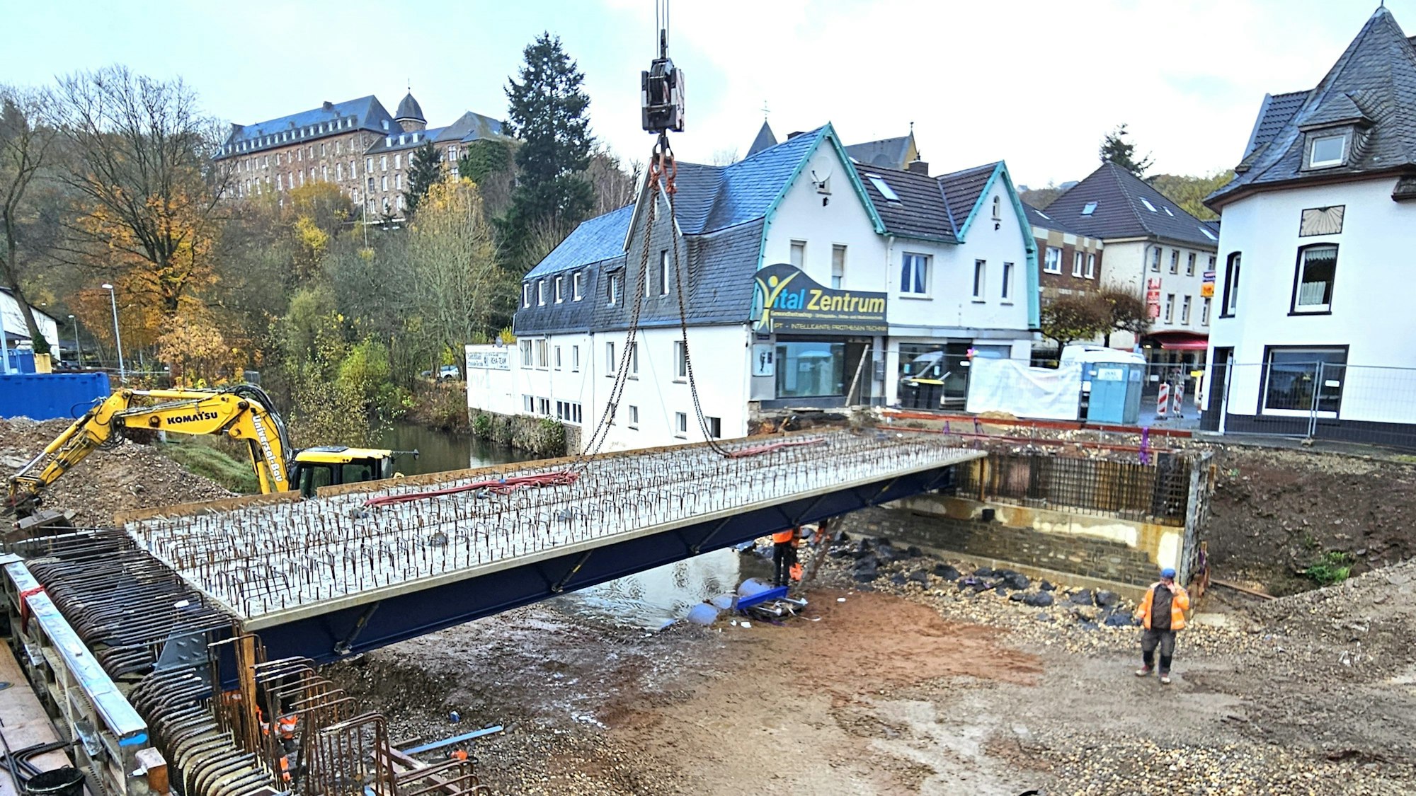 Zwei Brückenteile liegen schon auf den Widerlagern, an einem hängen noch die Taue des Krans.