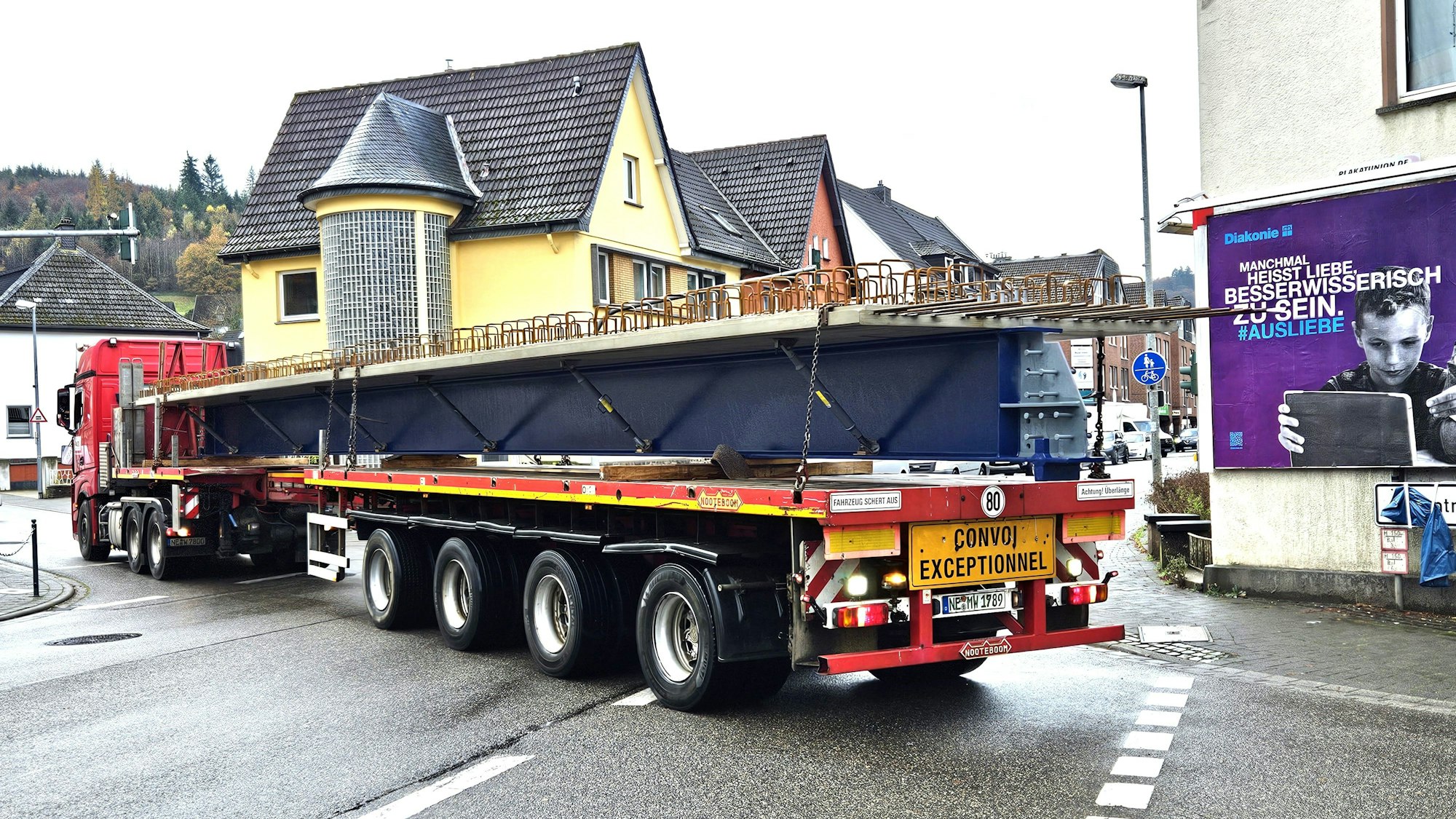 Blick auf einen rückwärts fahrenden Tieflader mit einem Träger auf der Ladefläche.