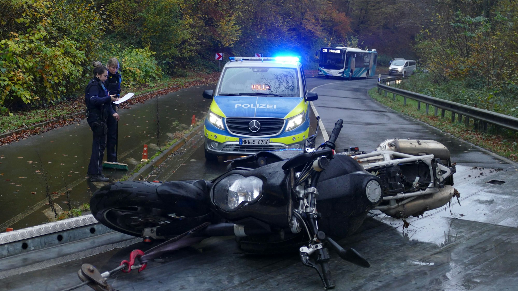 Ein Motorrad liegt auf einer Fahrbahn, dahinter steht ein Polizeifahrzeug.