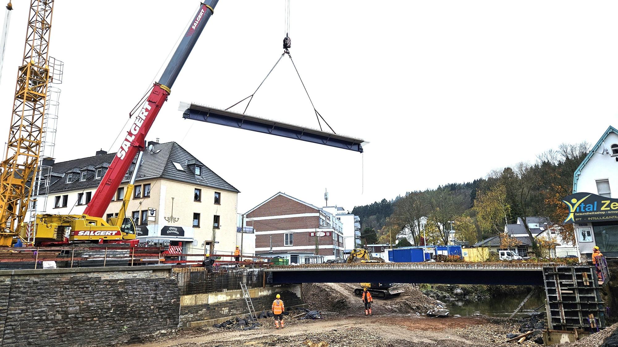 Ein Brückenteil hängt an den Seilen des Krans.