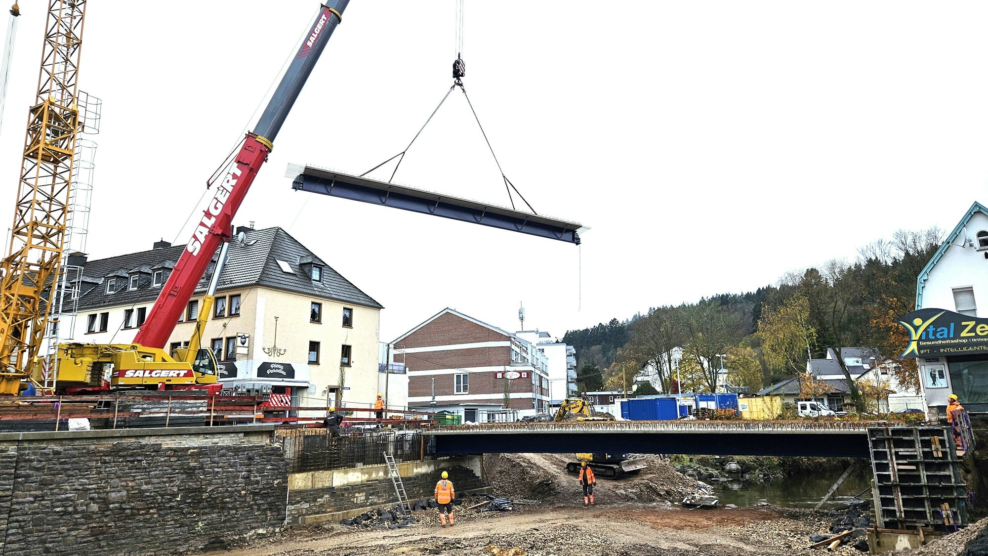 Ein Brückenteil hängt an den Seilen des Krans.