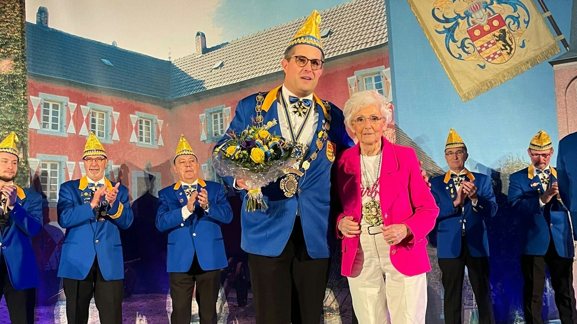 Karola Dänner steht neben Sven Hinterwälder, der einen Strauß Blumen hält.