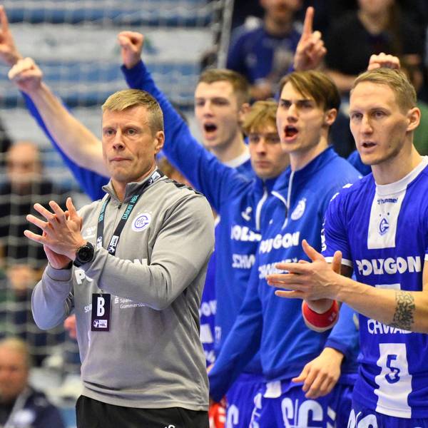 Mehrere Spieler des VfL Gummersbach und deren Trainer Gudjon Valur Sigurdsson jubeln am Rande eines Handballspiels.