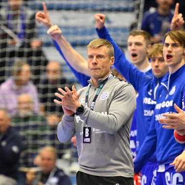 Mehrere Spieler des VfL Gummersbach und deren Trainer Gudjon Valur Sigurdsson jubeln am Rande eines Handballspiels.