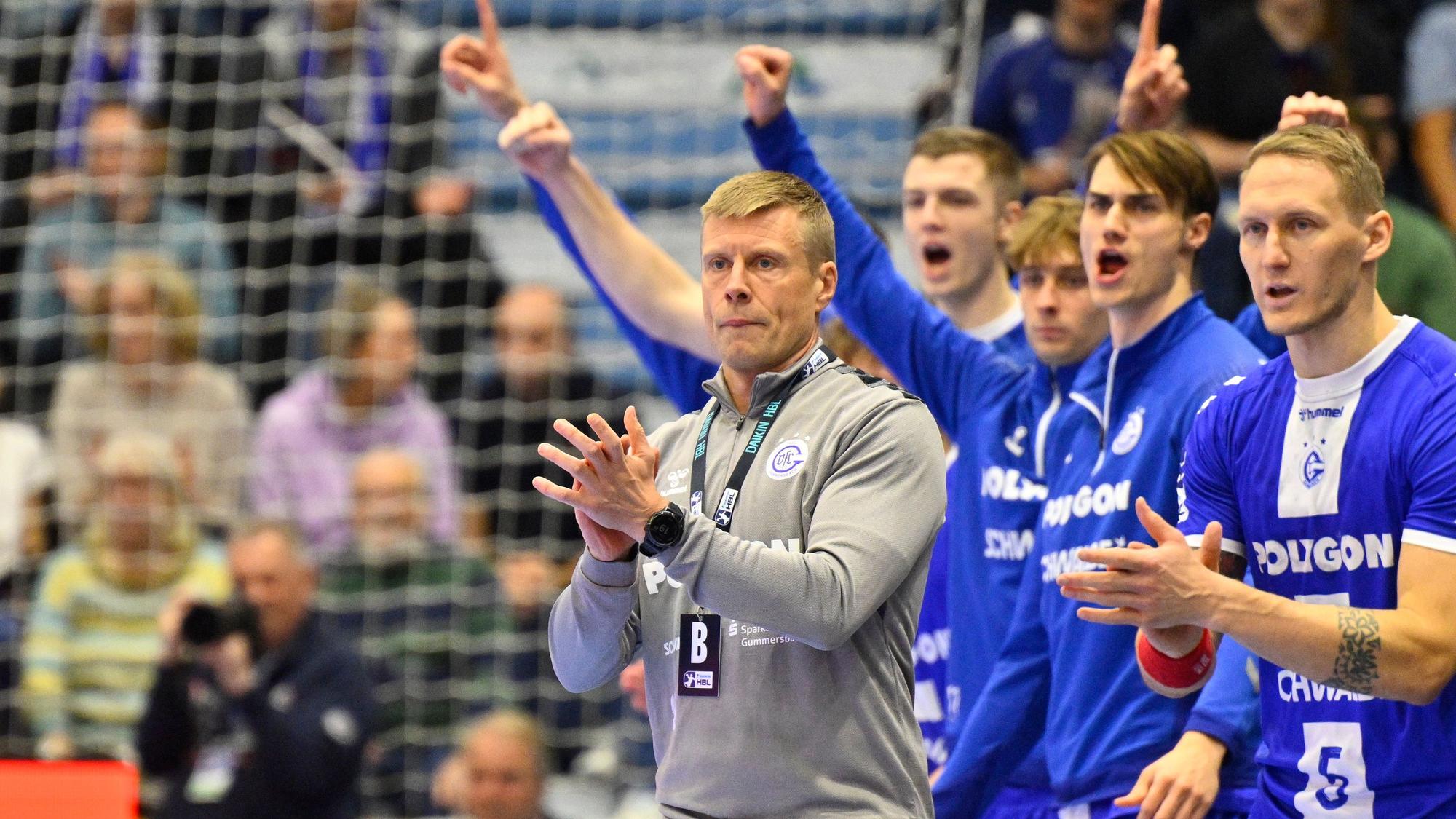 Mehrere Spieler des VfL Gummersbach und deren Trainer Gudjon Valur Sigurdsson jubeln am Rande eines Handballspiels.