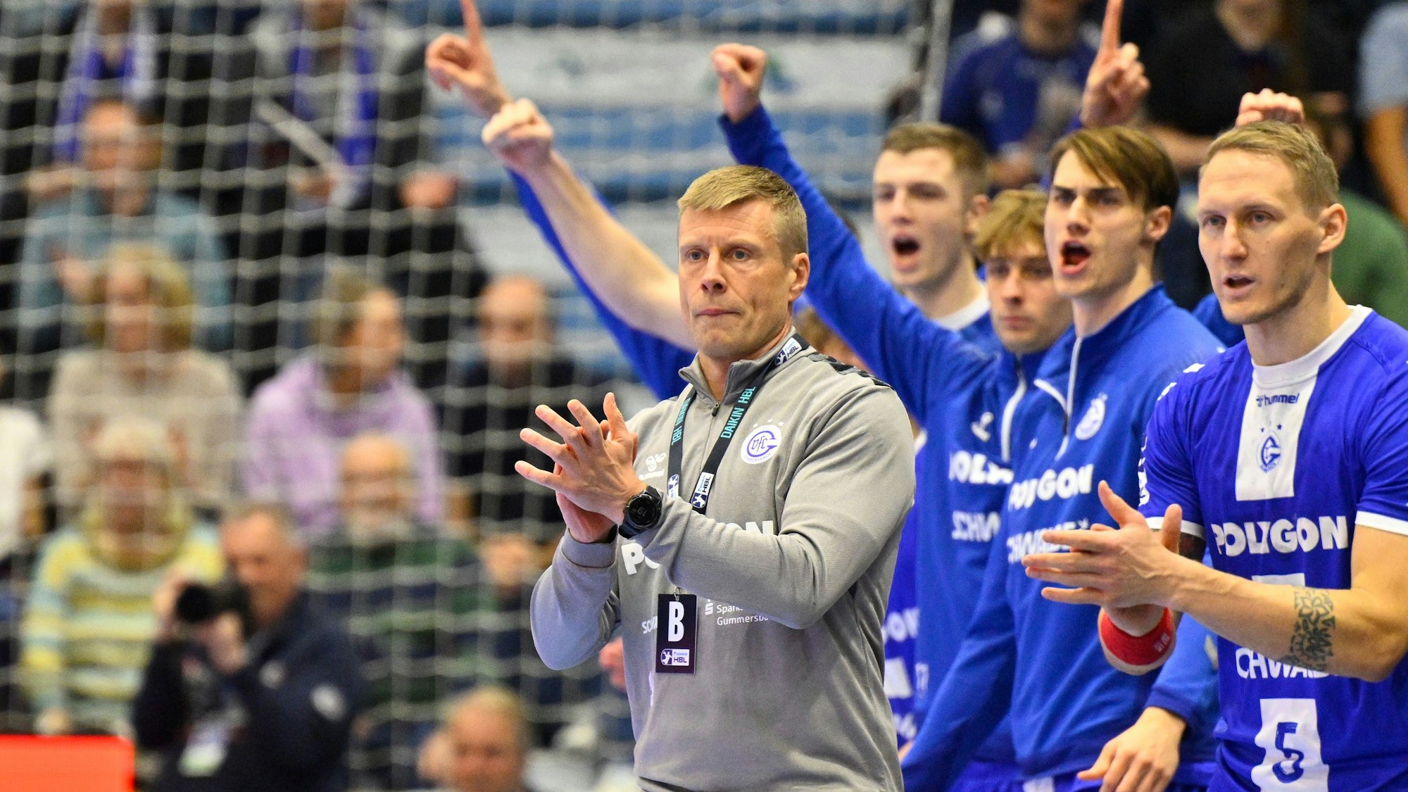 Mehrere Spieler des VfL Gummersbach und deren Trainer Gudjon Valur Sigurdsson jubeln am Rande eines Handballspiels.