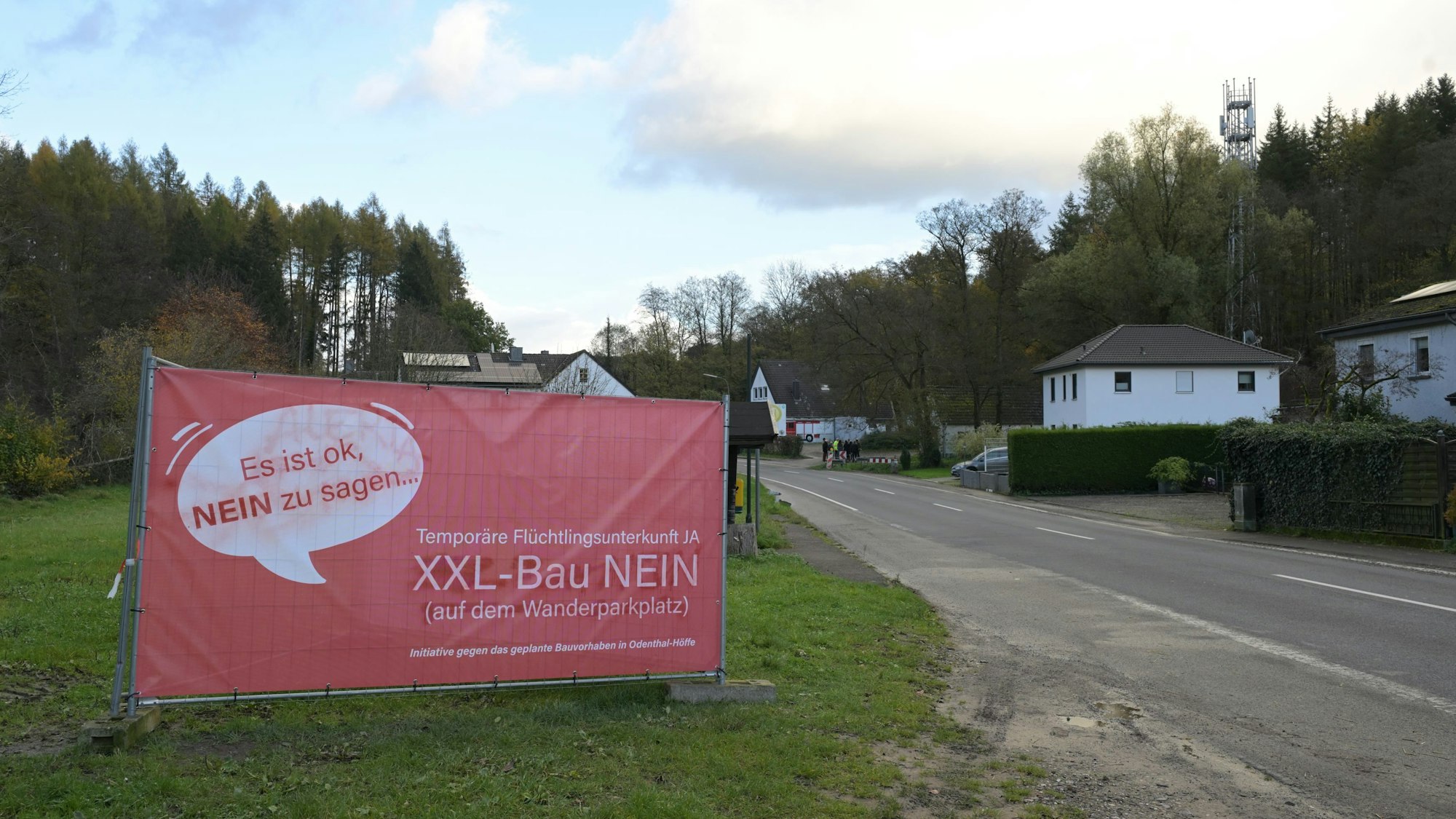 Ein rotes Plakat steht an einer Straße. Darauf protestiert eine Bürgerinitiative gegen den Bau eines Flüchtlingsheims.