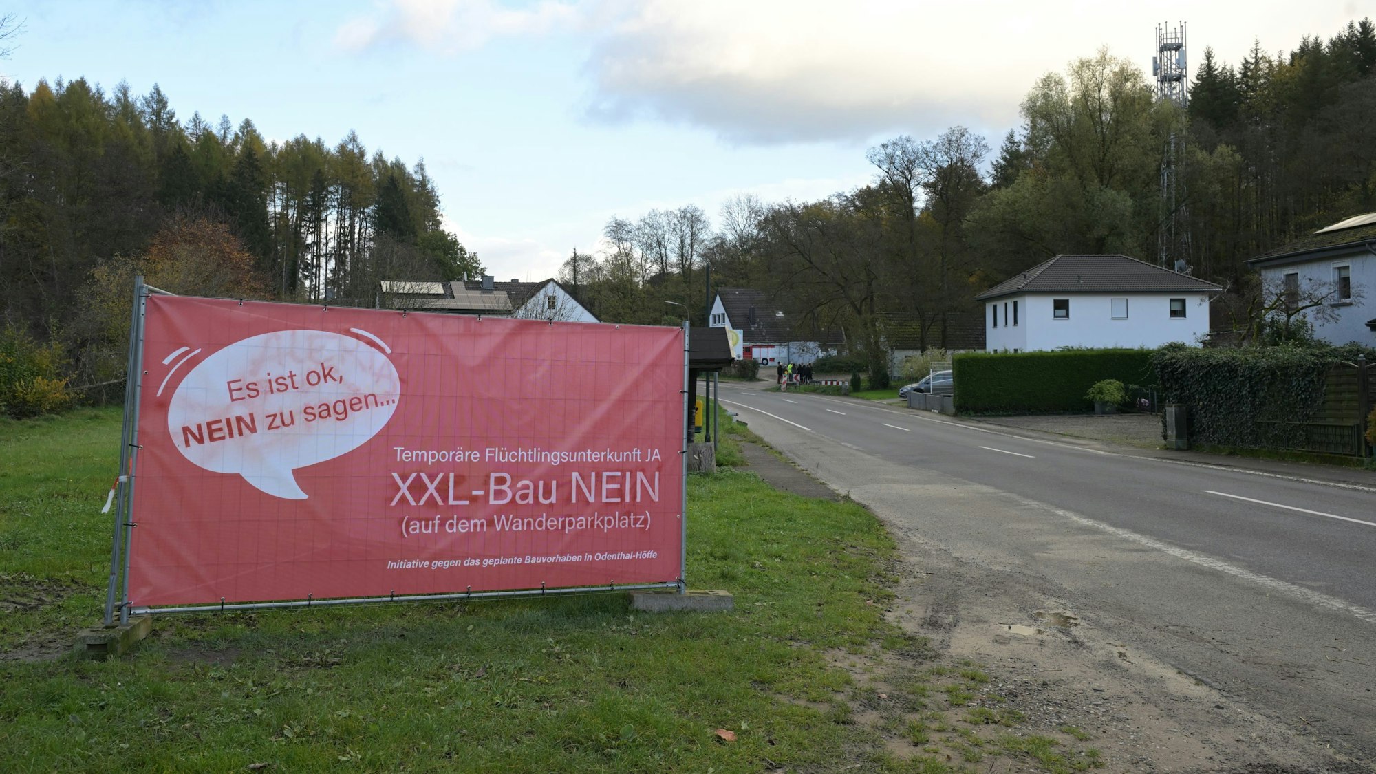 Ein großes, rotes Plakat weist auf Protest gegen den Bau einer Flüchtlingsunterkunft hin.