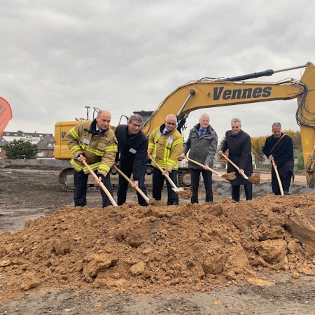 Zu sehen sind sechs für den Bau verantwortliche Männer, die einen Spaten in der Hand halten.