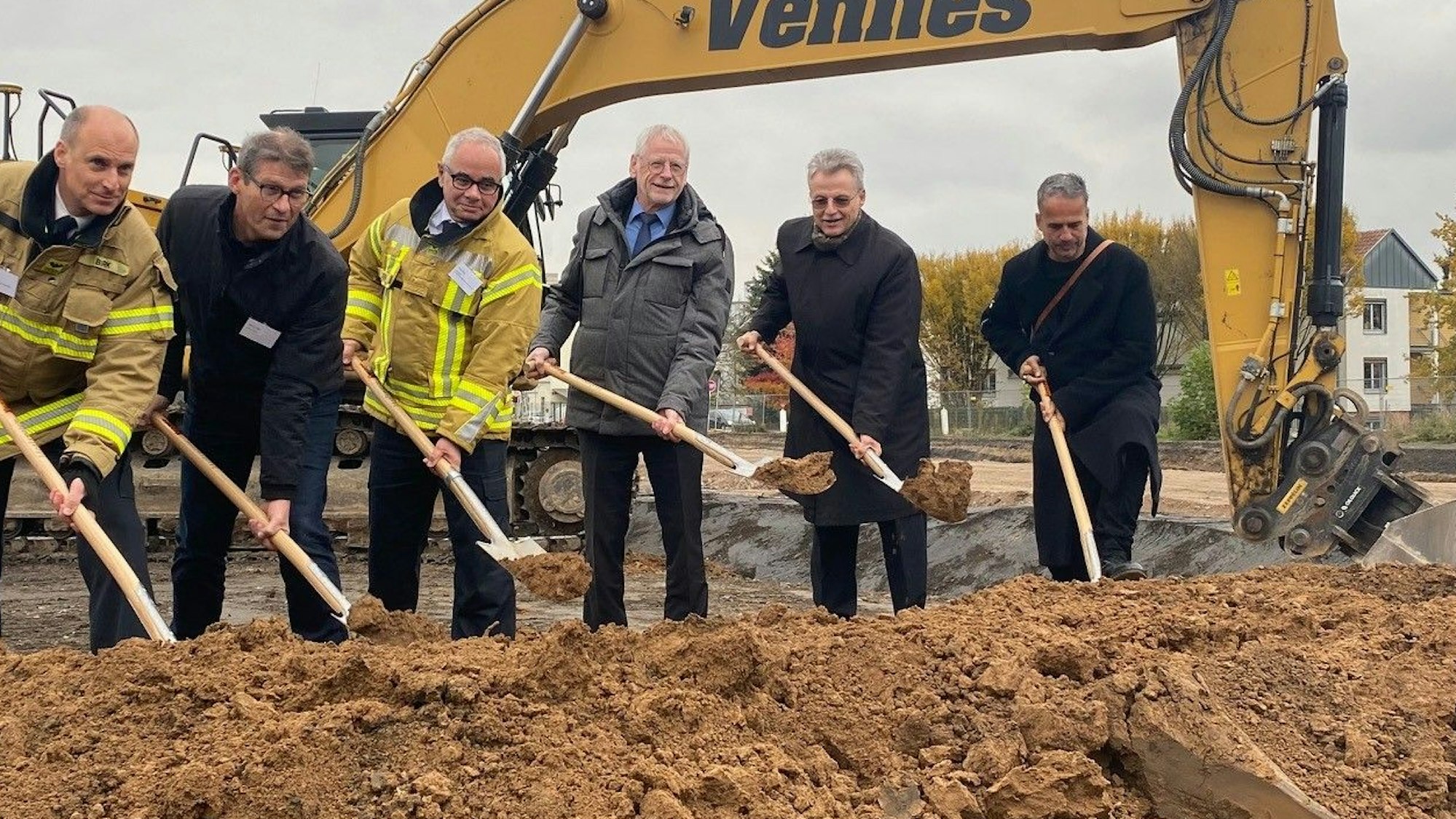 Zu sehen sind sechs für den Bau verantwortliche Männer, die einen Spaten in der Hand halten.