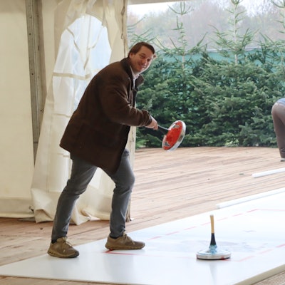 Auf dem Bild ist ein Mann zu sehen, der eine Eisstock-Bahn testet.