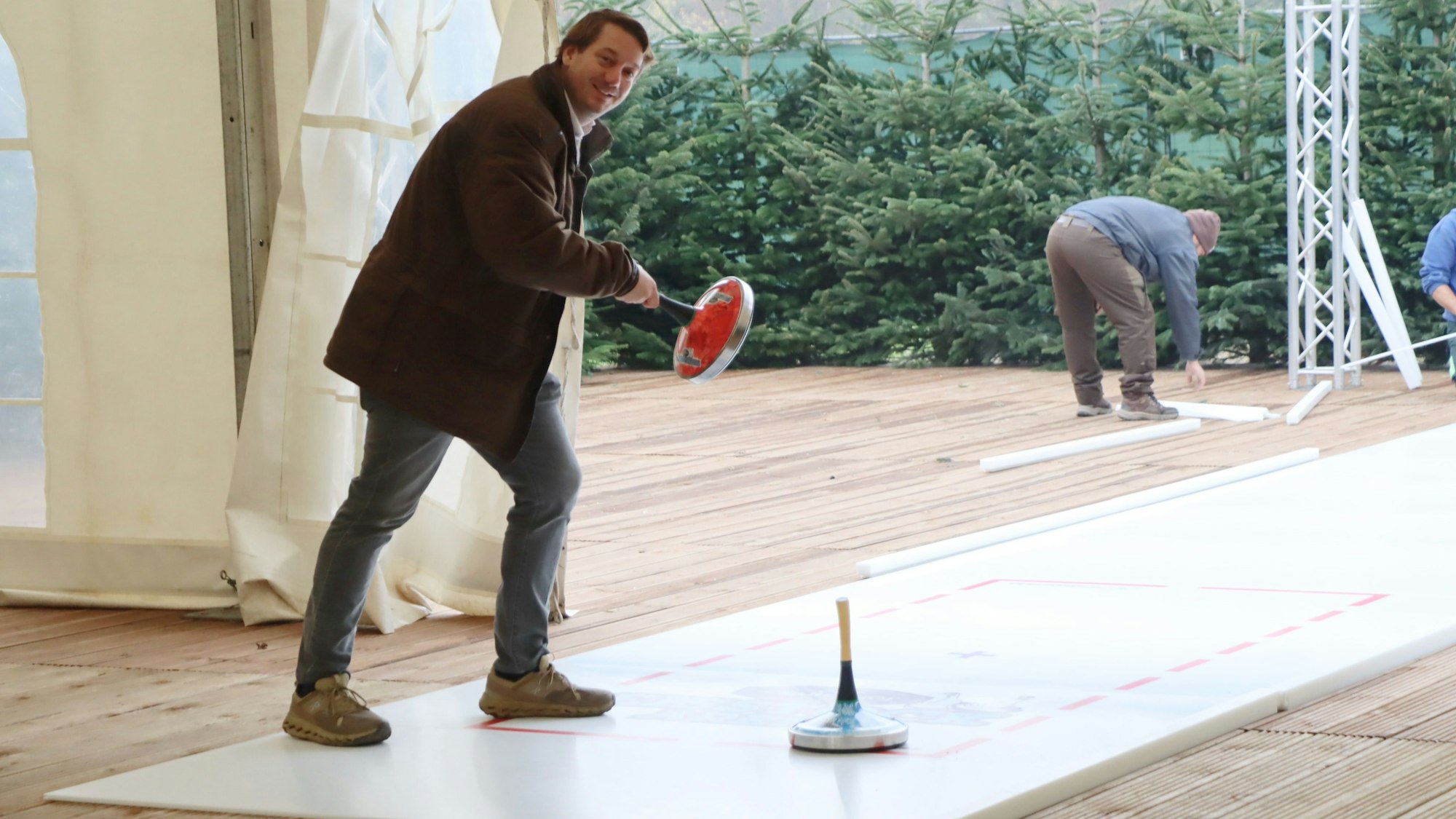 Auf dem Bild ist ein Mann zu sehen, der eine Eisstock-Bahn testet.