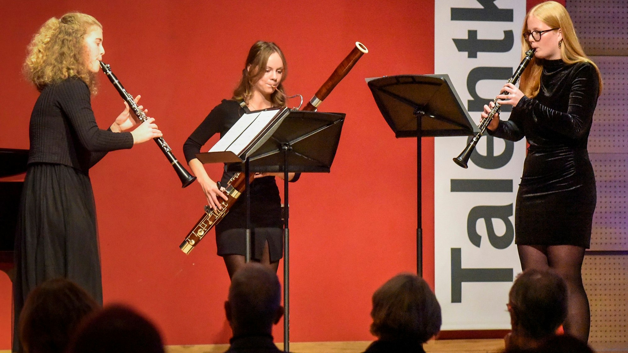 Das Foto zeigt drei junge Musikerinnen mit ihren Blasinstrumenten.
