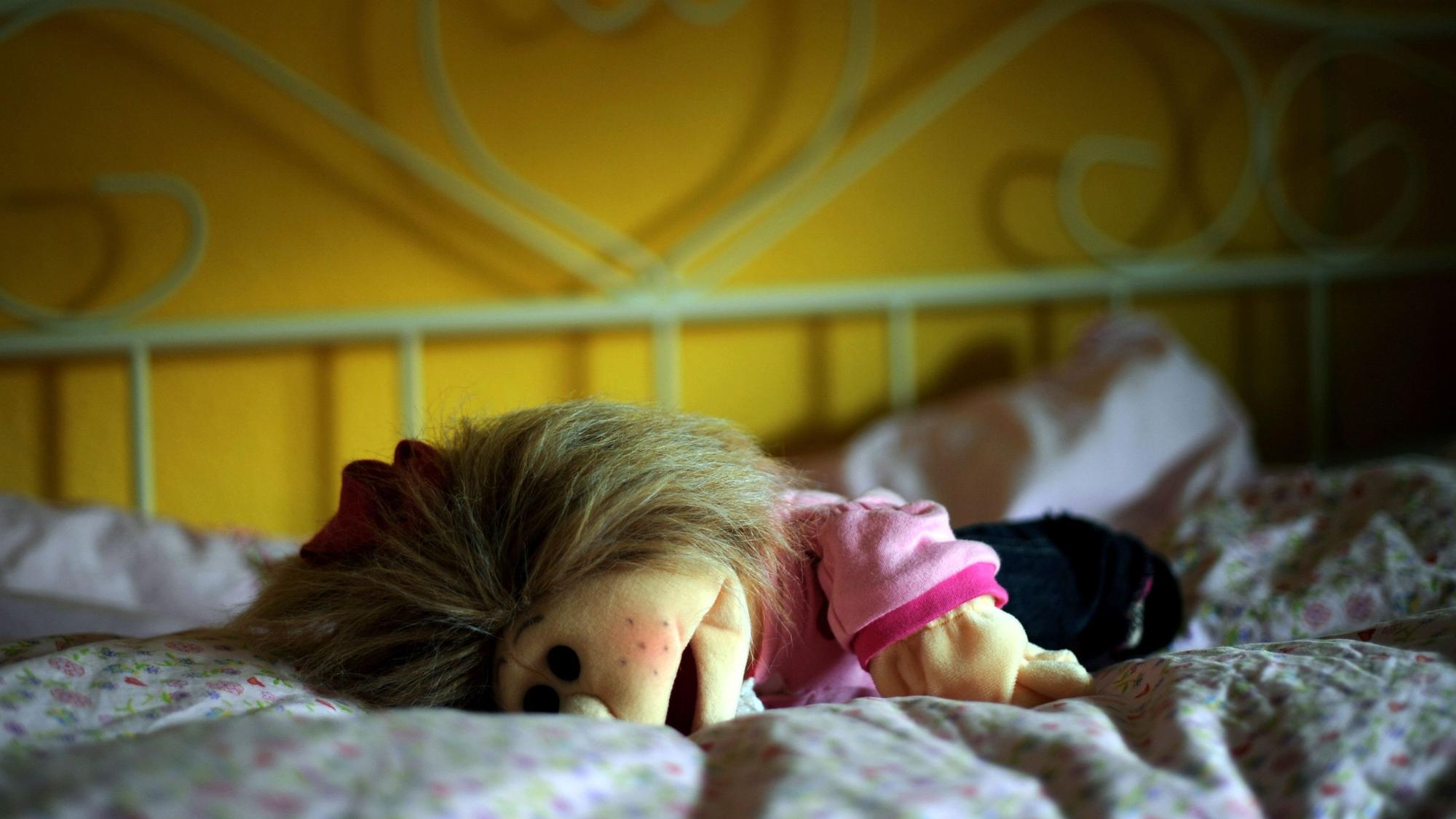 Eine Puppe liegt in Kassel in einem Kinderzimmer auf dem Bett.