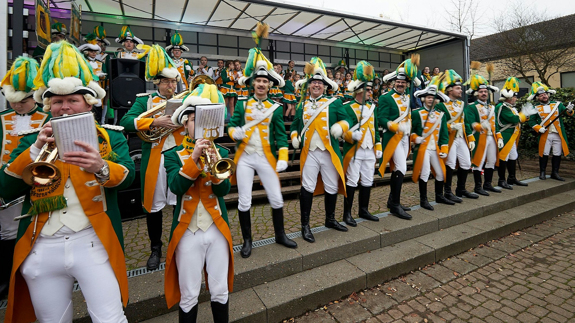 Zahlreiche Karnevalisten spielen ihre Musikinstrumente und stehen in Reih und Glied.