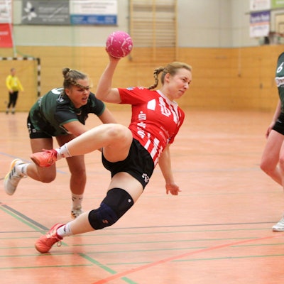 Eine Handballerin wirft den ganzen Körper in den Wurf und liegt schräg in der Luft.