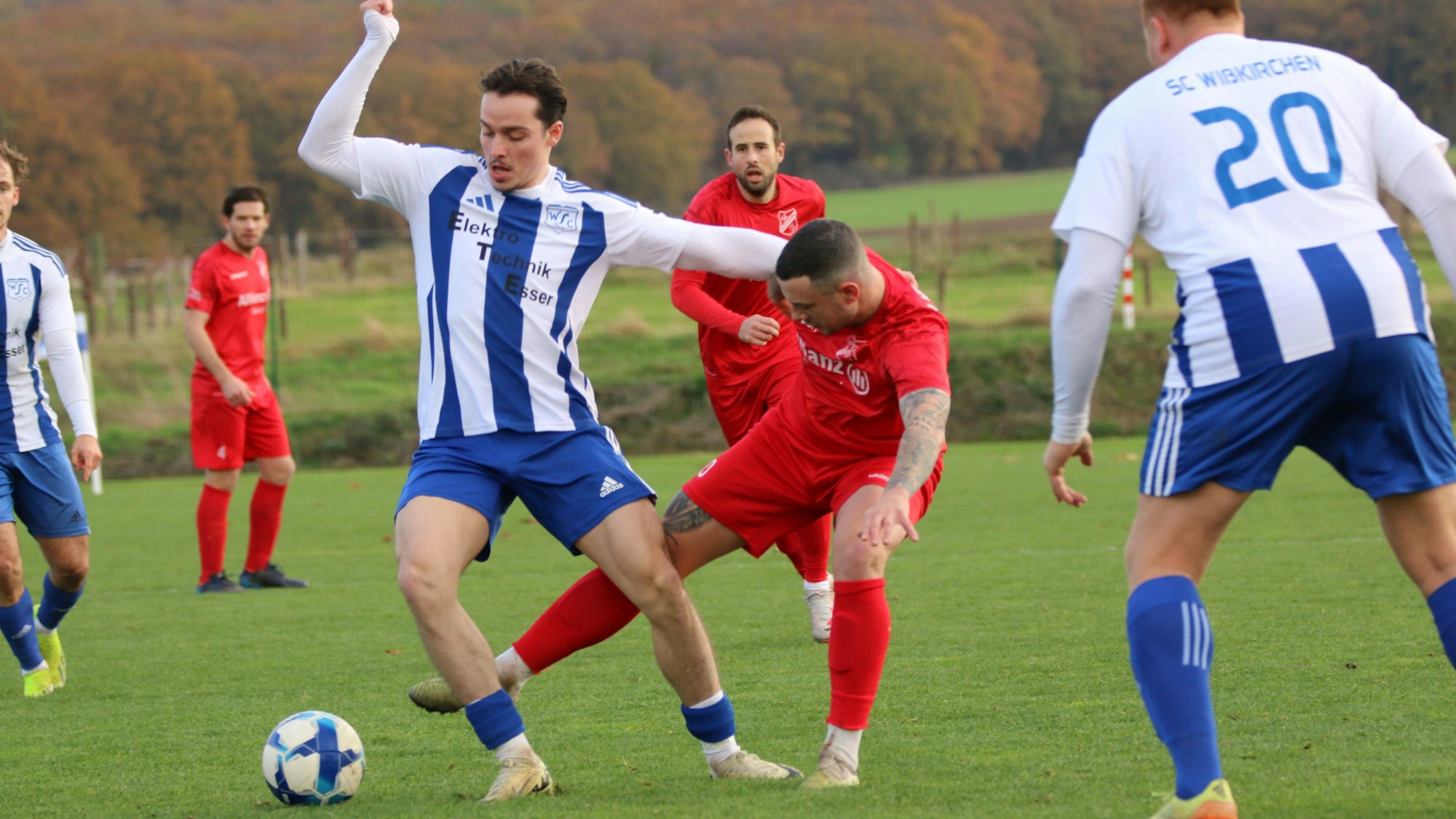 Mit dem Arm hält sich ein Fußballer den Gegenspieler vom Leib, der gleichzeitig von hinten versucht, an den Ball zu gelangen.