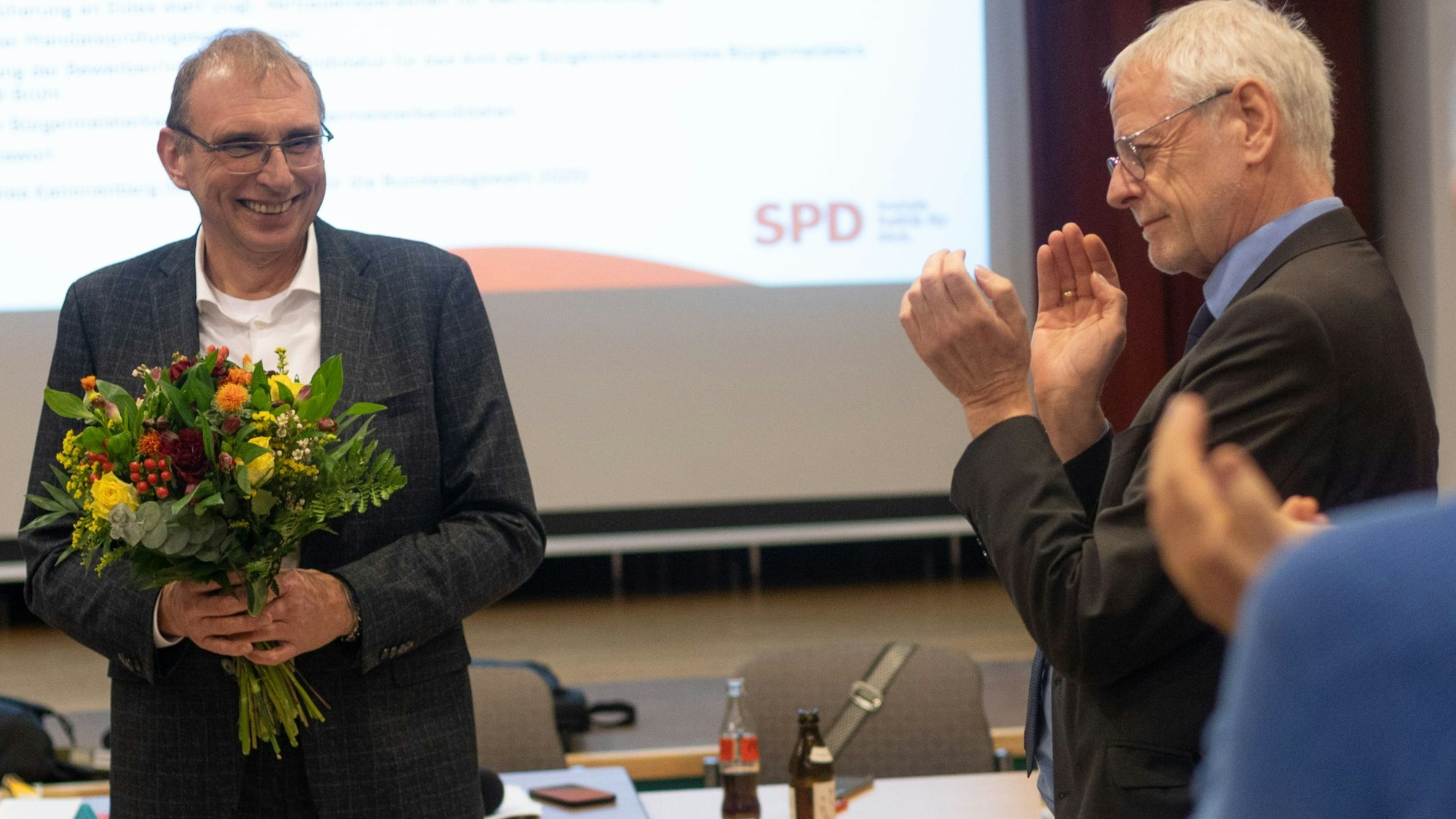 Auf dem Foto ist ein Mann zu sehen, der einen Blumenstrauß in seinen Händen hält.