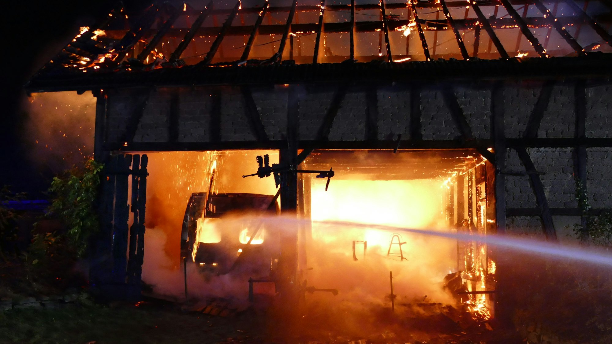 Der Umriss eines Autos ist in einer brennenden Scheune zu sehen.
