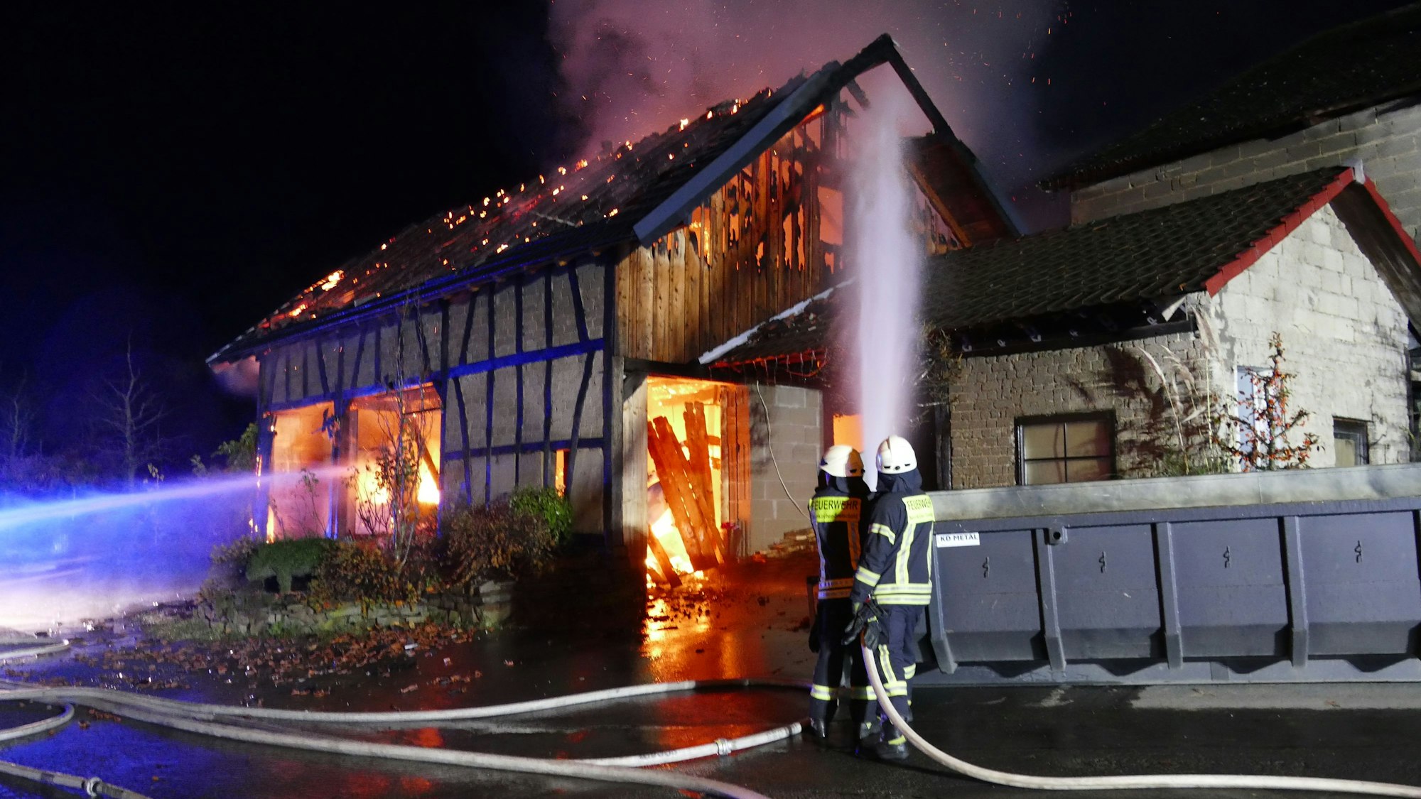 Feuerwehrleute löschen eine brennende Scheune.