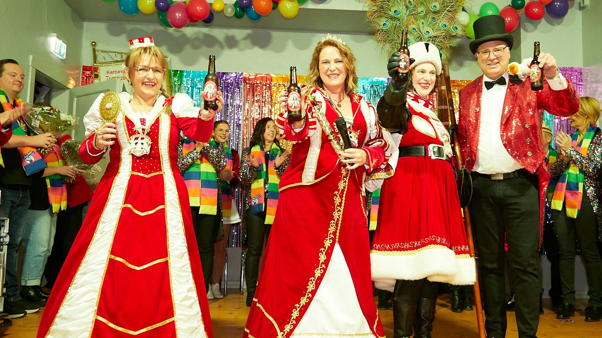 Das Bild zeigt die Tollitäten aus Hasenfeld, die mit Bürgermeister Jochen Weiler Bierflaschen in die Kamera halten.