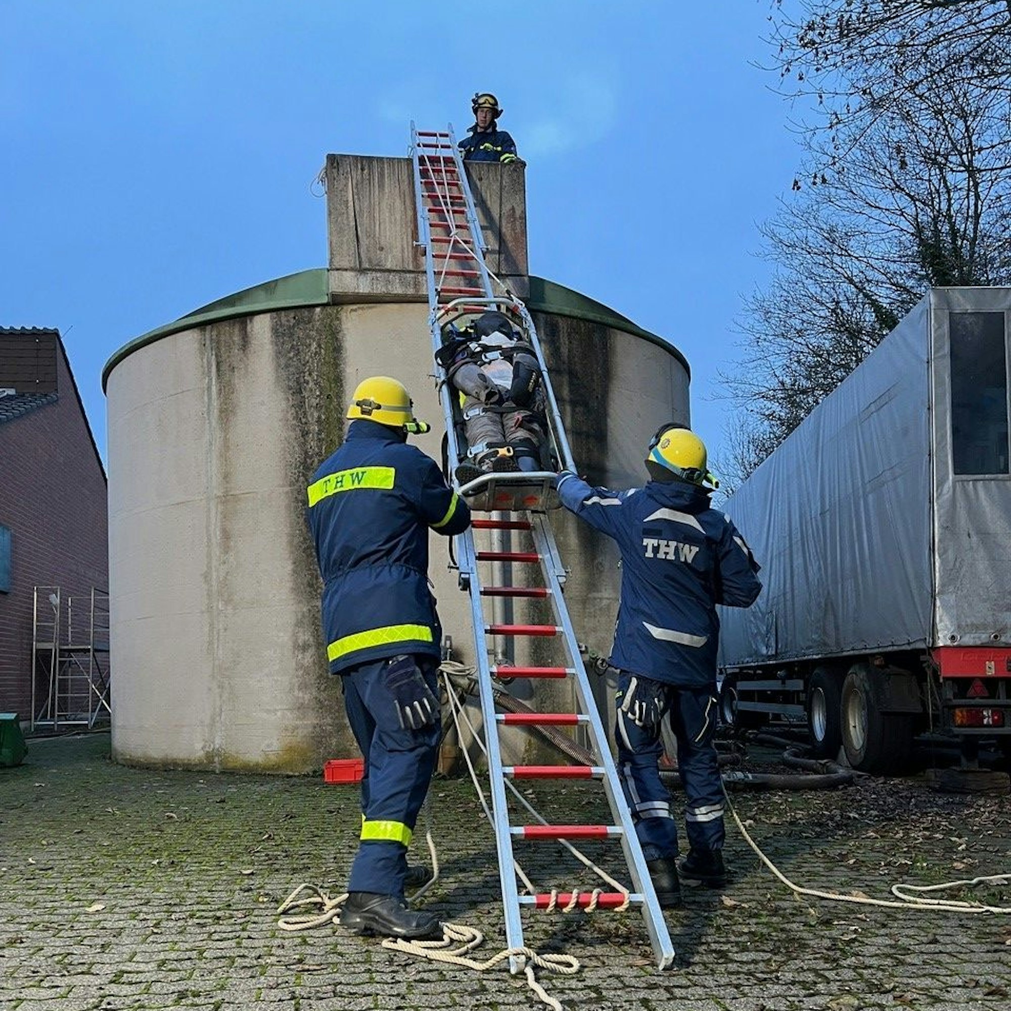Das Bild zeigt die Rettung eines verunglückten Mitarbeiters, der mithilfe einer Leiter aus der Höhe gerettet wird.