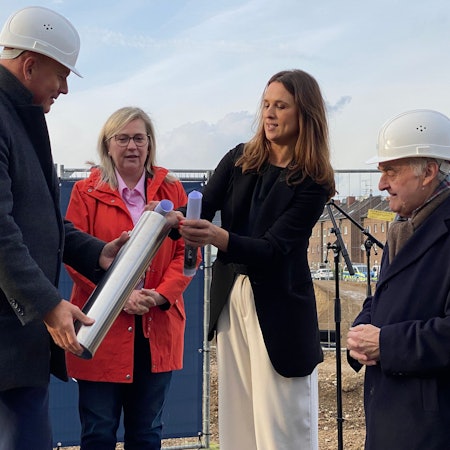 Zu sehen sind die für den Bau verantwortlichen Frauen und Männer, die die Zeitkapsel füllen.