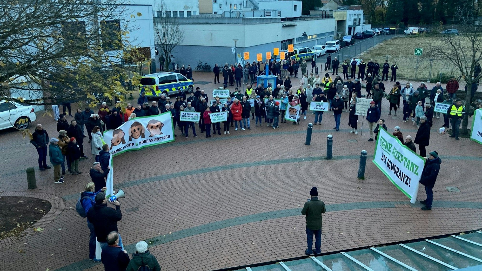 Auf dem Bild sind Menschen mit Transparenten und Schildern vor dem Stadtsaal in Frechen zu sehen.
