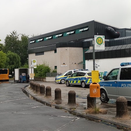Mehrere Streifenwagen stehen vor einer Versammlungshalle