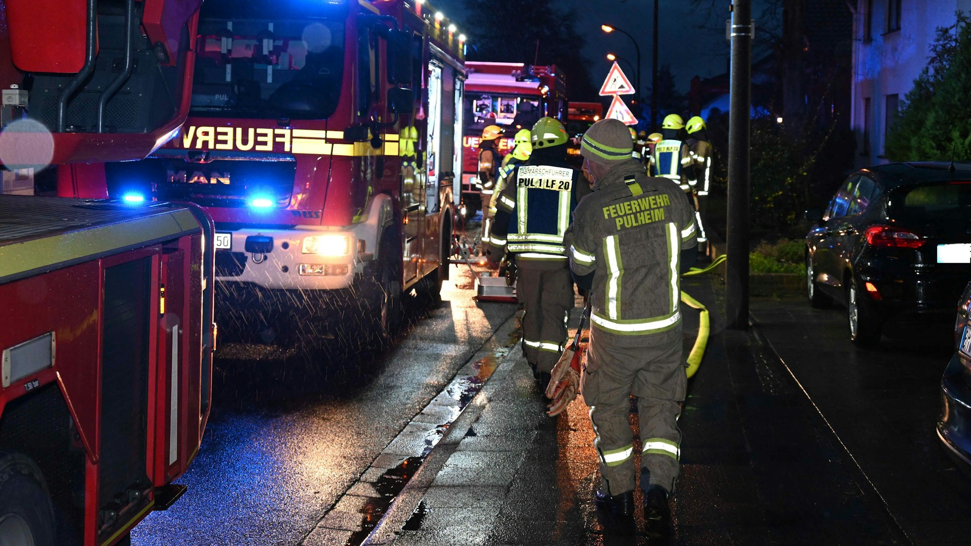 Auf dem Bild sind Feuerwehrleute im Einsatz und zwei Löschfahrzeuge zu sehen.