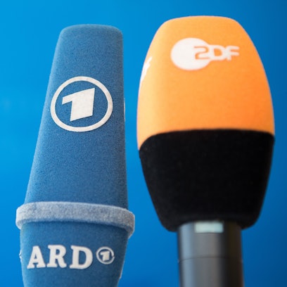 Die Mikrofone von ARD und ZDF sind vor einer Pressekonferenz nebeneinander aufgestellt.