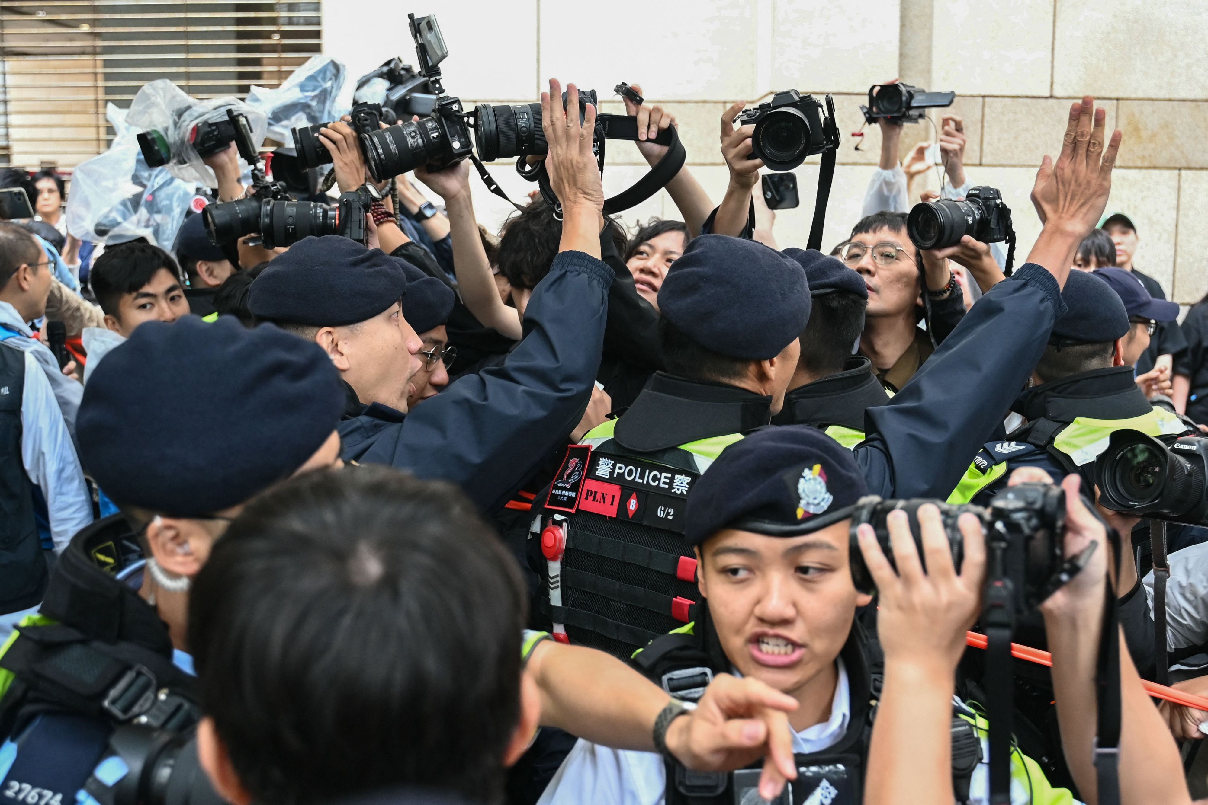 Polizeibeamte Hongkongs halten Fotografen zurück.