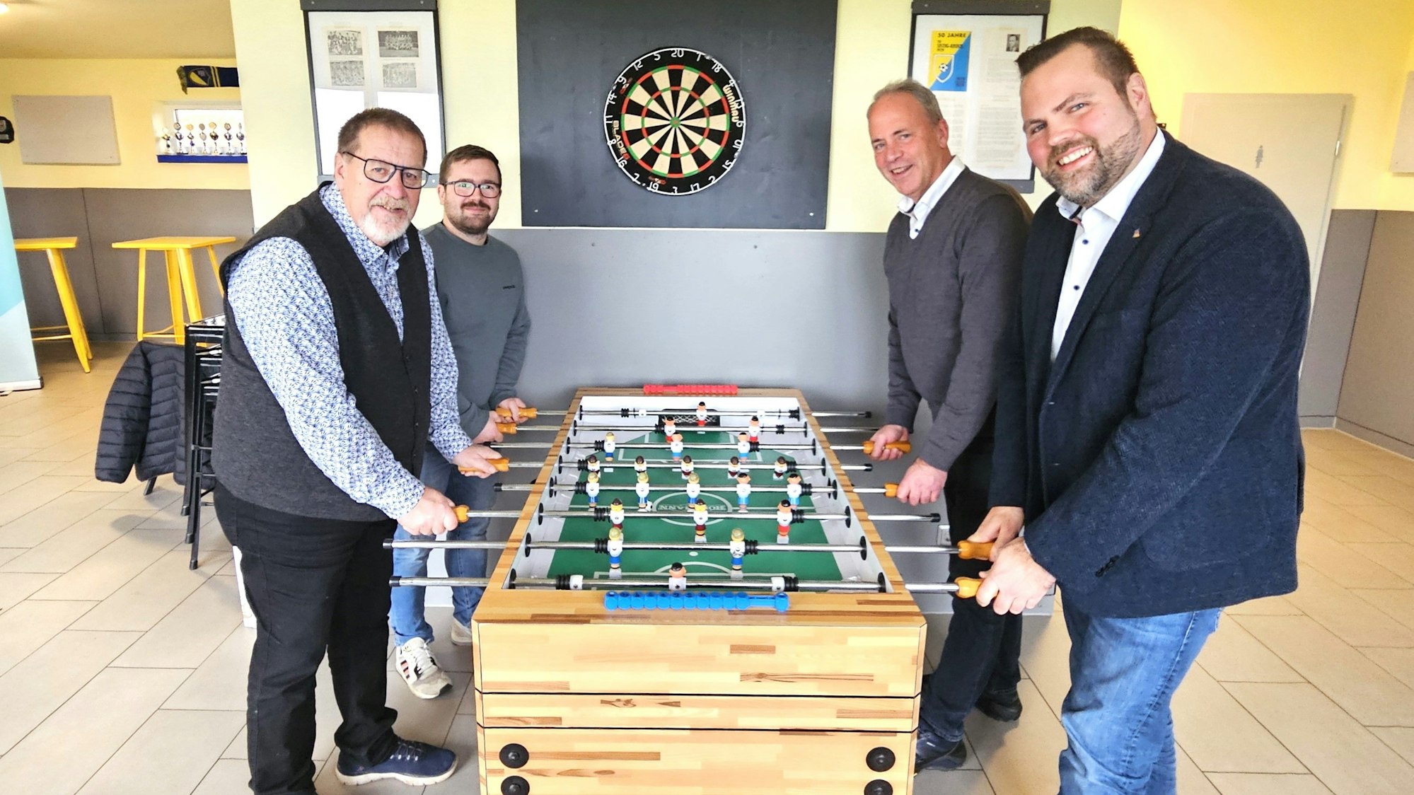 Michael Kehren, Bert Spilles, Brian Linden und Hermann-Josef Esser stehen an einem Fußballkicker.