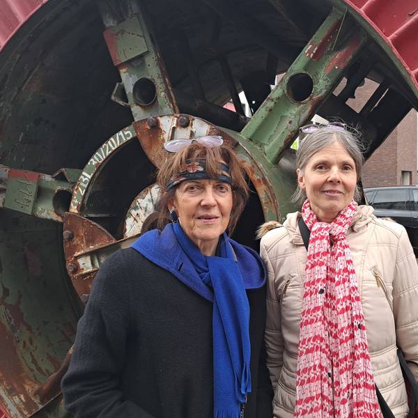 Zwei Frauen stehen vor einem ausrangierten Industrie-Denkmal.