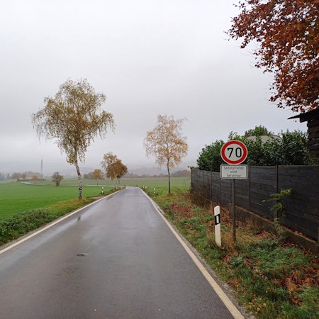 Das Bild zeigt die Kreisstraße 45 von Eschweiler in Richtung Iversheim. Auf der rechten Seite steht ein Tempo-70-Schild. Die Straße ist nass.
