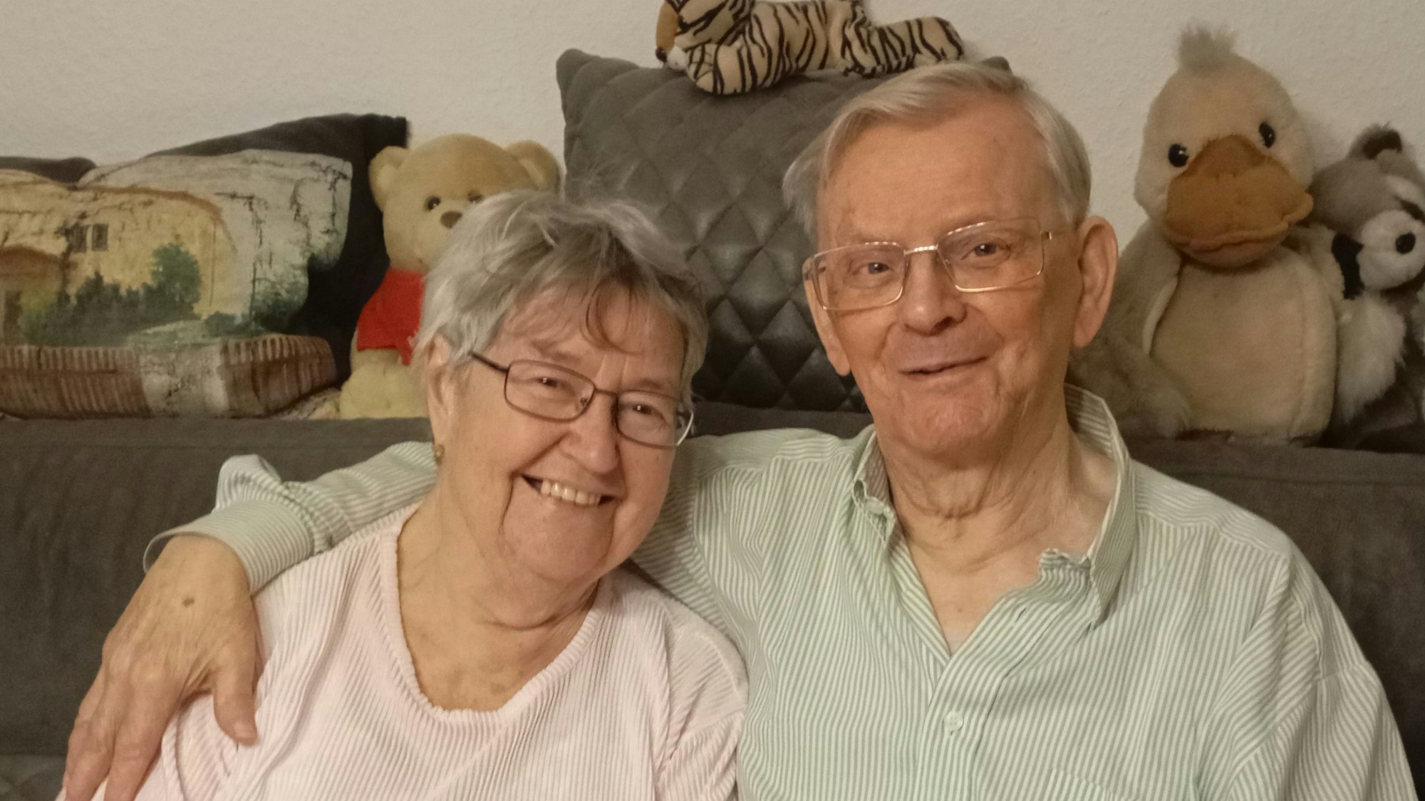 Das Ehepaar sitzt auf dem Sofa und lächelt, Wilhelm Reukauf hat den Arm um seine Ehefrau Ursula Reukauf gelegt.