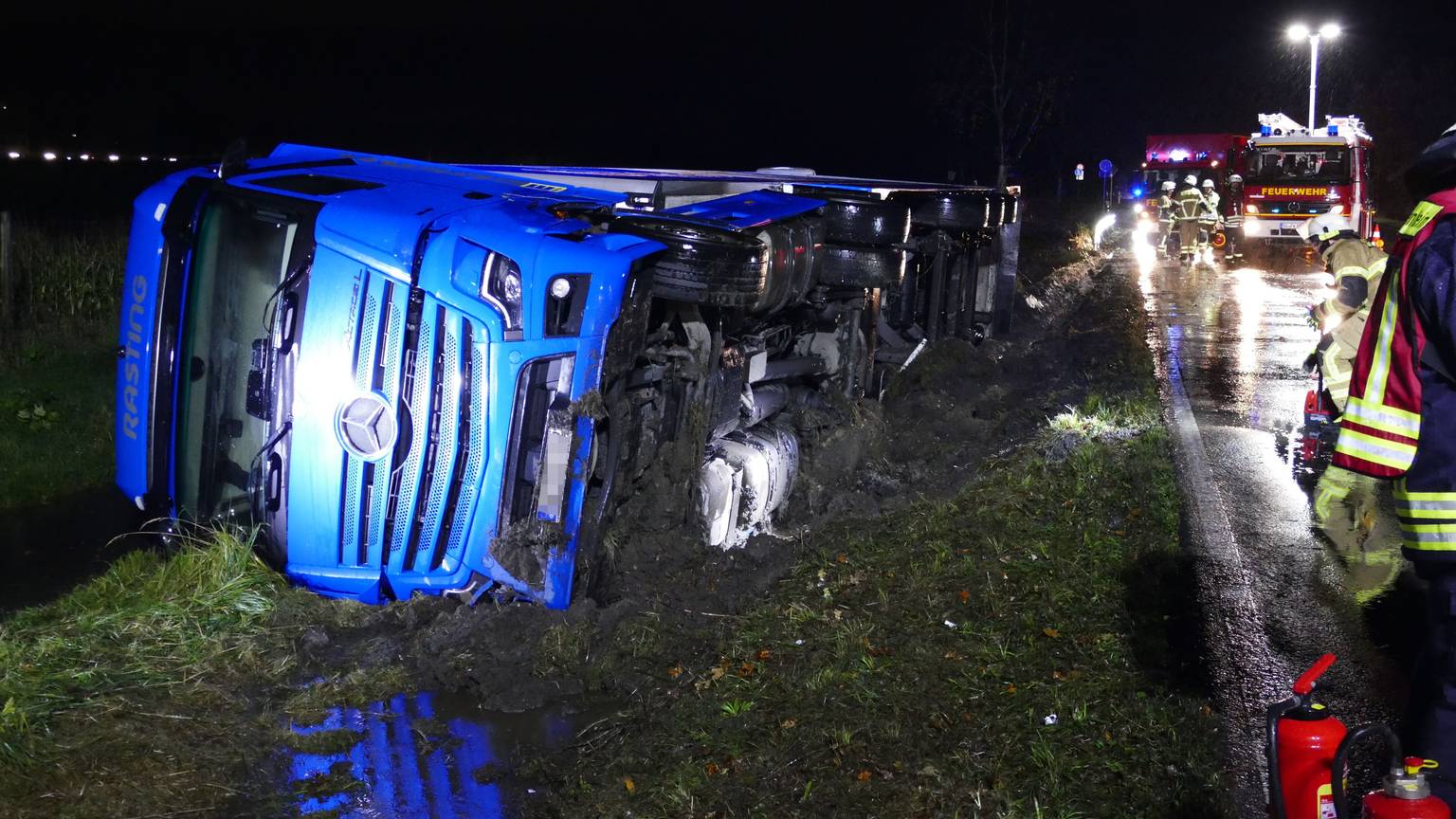 Ein Lkw liegt seitlich im Straßengraben.