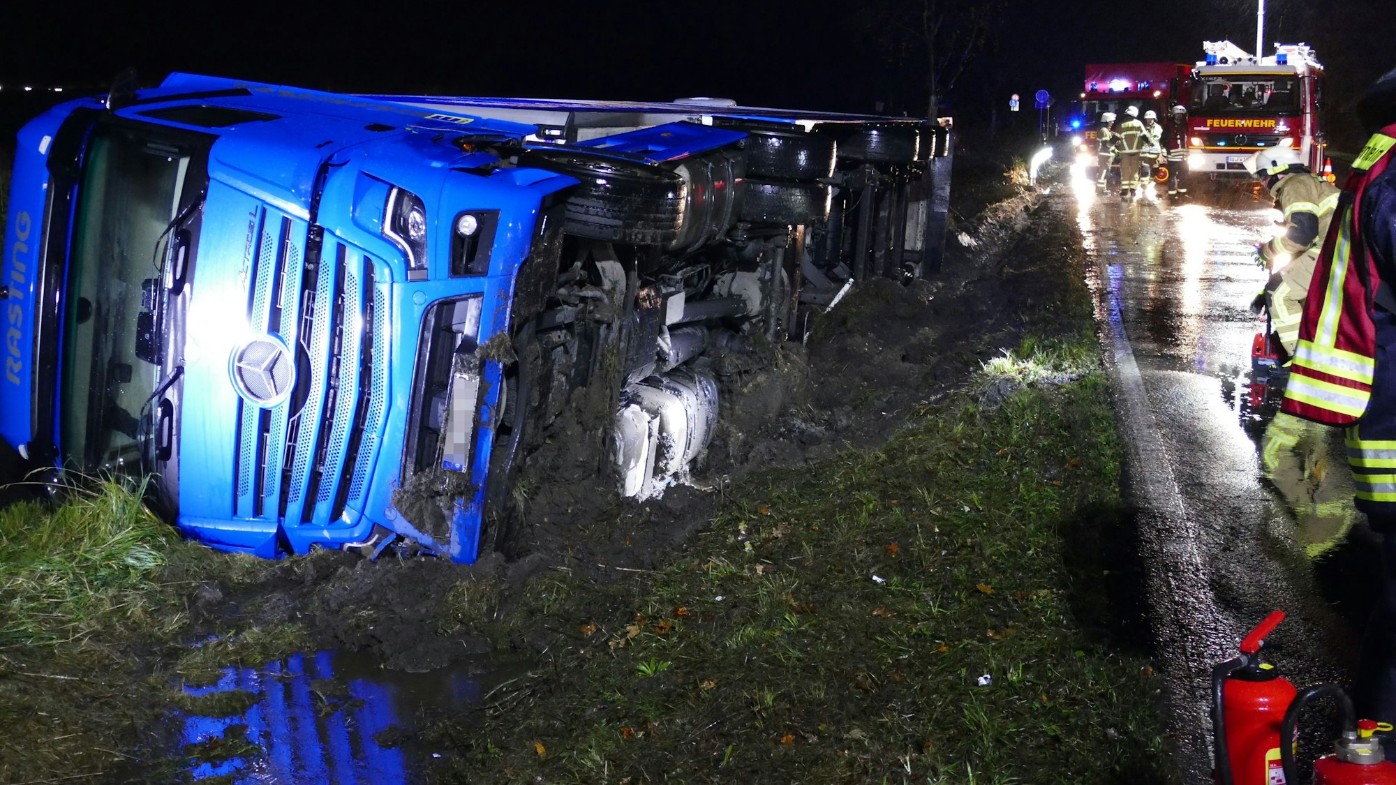 Ein Lkw liegt seitlich im Straßengraben.