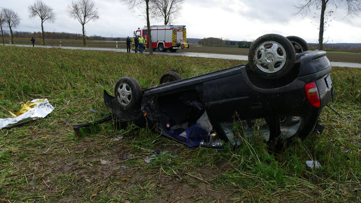 Ein Auto liegt auf dem Dach auf einer Wiese.