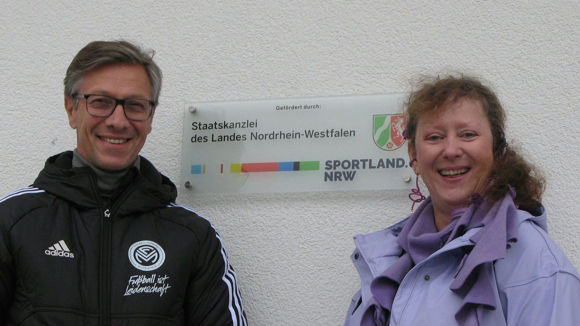 Ein Mann und eine Frau an einem Schild der Staatskanzler des Landes Nordrhein-Westfalen.