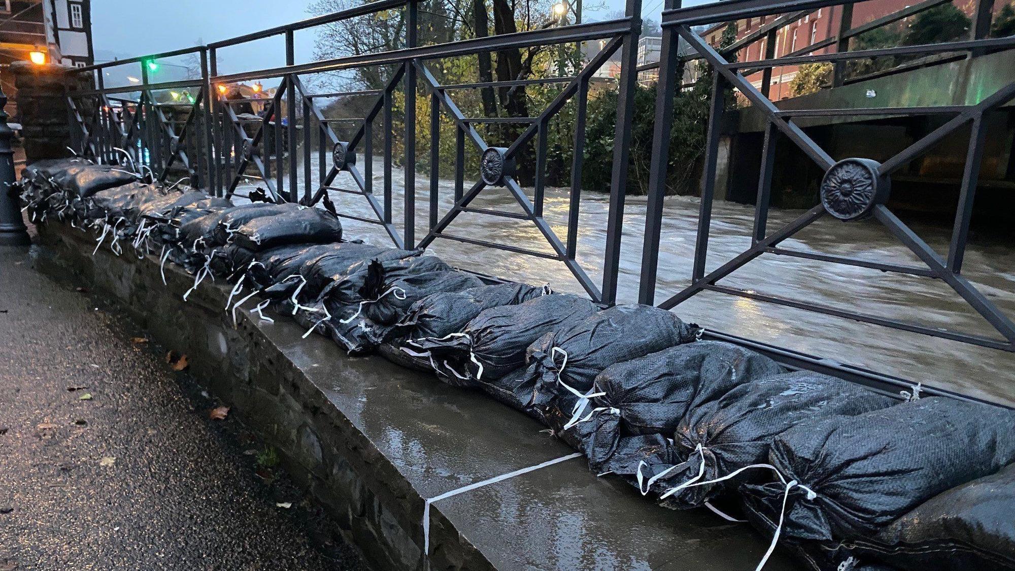 Sandsäcke sollen die Ufer des Deilbachs in Velbert-Langenberg schützen. Aufgrund des Dauerregens sind in dem Ortsteil Keller vollgelaufen und Straßen überflutet.