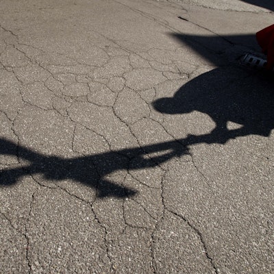 Der Schatten eines Priesters, der am Karfreitag bei einer Zeremonie ein Kreuz trägt, fällt auf das Pflaster.