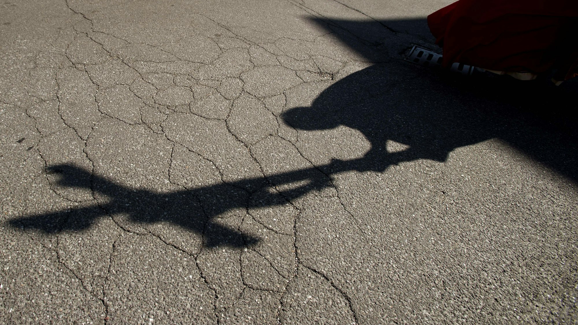 Der Schatten eines Priesters, der am Karfreitag bei einer Zeremonie ein Kreuz trägt, fällt auf das Pflaster.