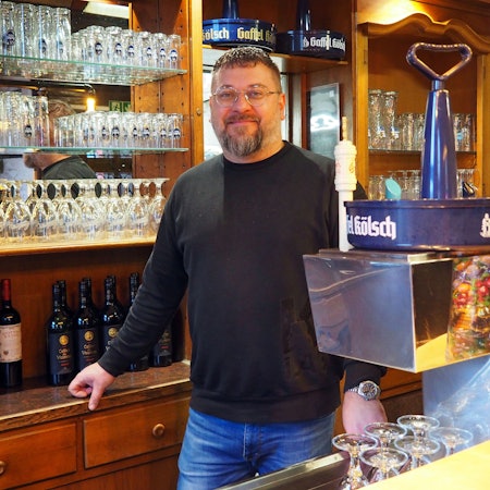 Der Gastronom Michael Sardis steht hinter der Theke seines Restaurants „Kölsche Heimat“ in Zollstock.