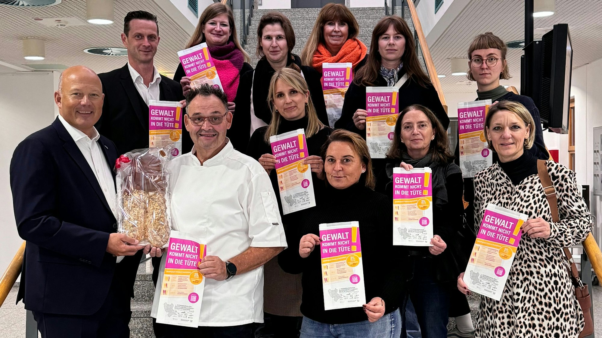 Landrat Frank Rock (links) und die Gleichstellungsbeauftragte Julia Willems (2. Reihe, Mitte) präsentieren mit Unterstützern und Bäckerei-Vertretern die Brötchentüten der Kampagne „Gewalt kommt uns nicht in die Tüte!“.