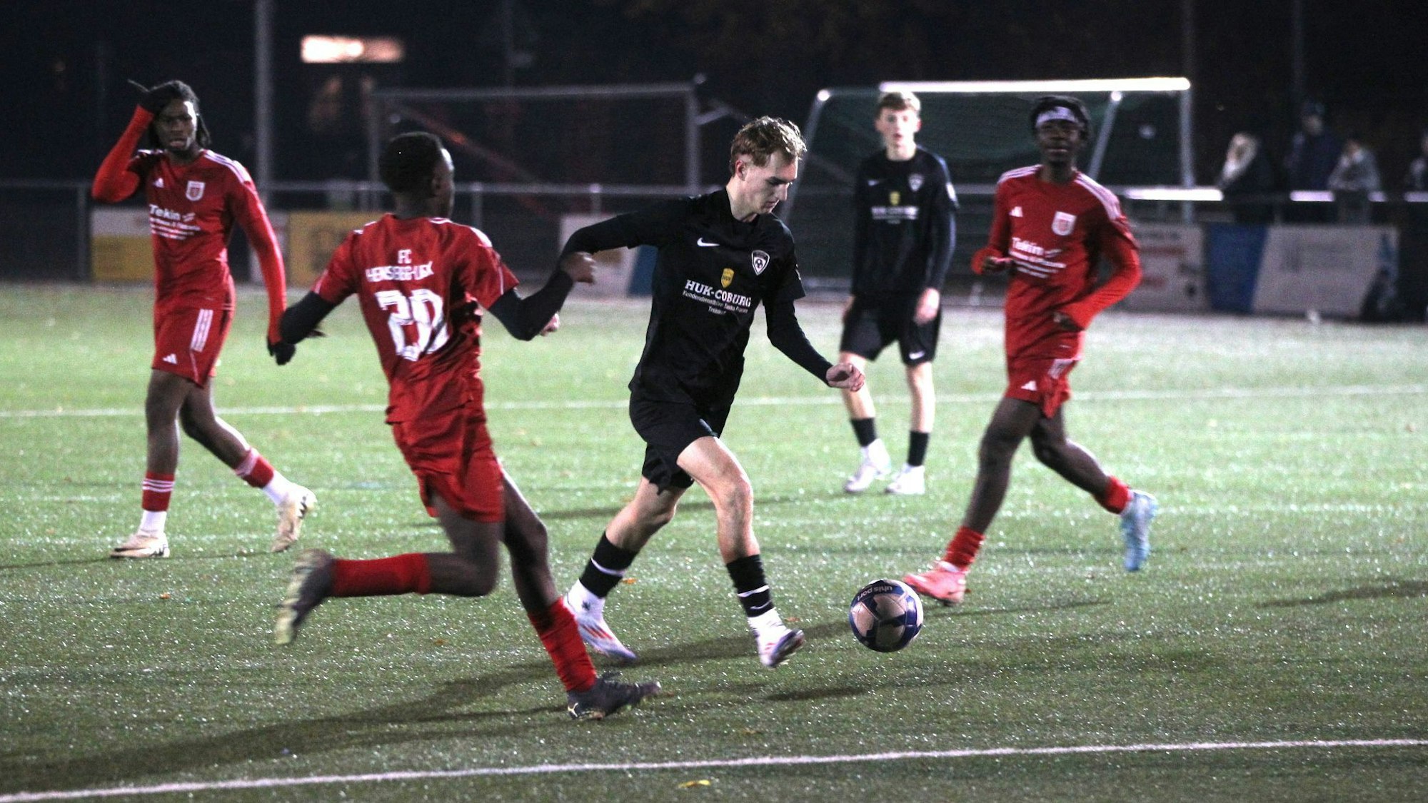 Ein Fußballer setzt zum Torschuss an, die Verteidiger kommen zu spät.