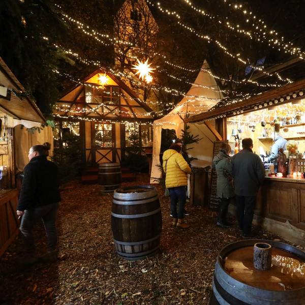 Eine Holzbude, an der es Getränke gibt, im Hintergrund eine Berghütte.