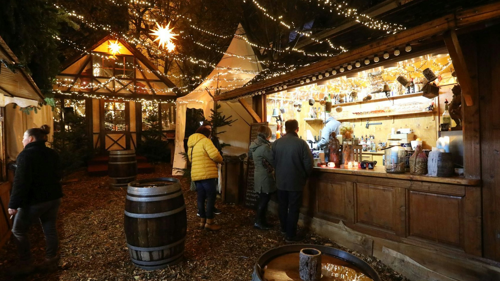 Eine Holzbude, an der es Getränke gibt, im Hintergrund eine Berghütte.