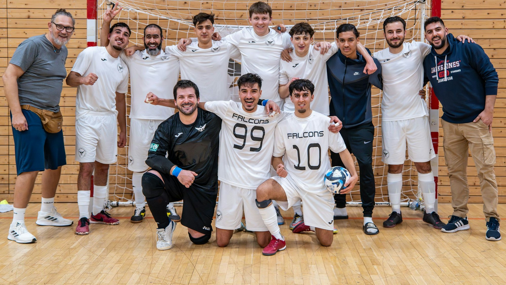 Das Bild zeigt die Spieler der Bergheim Falcons in weißen Trikots vor einem Handballtor.