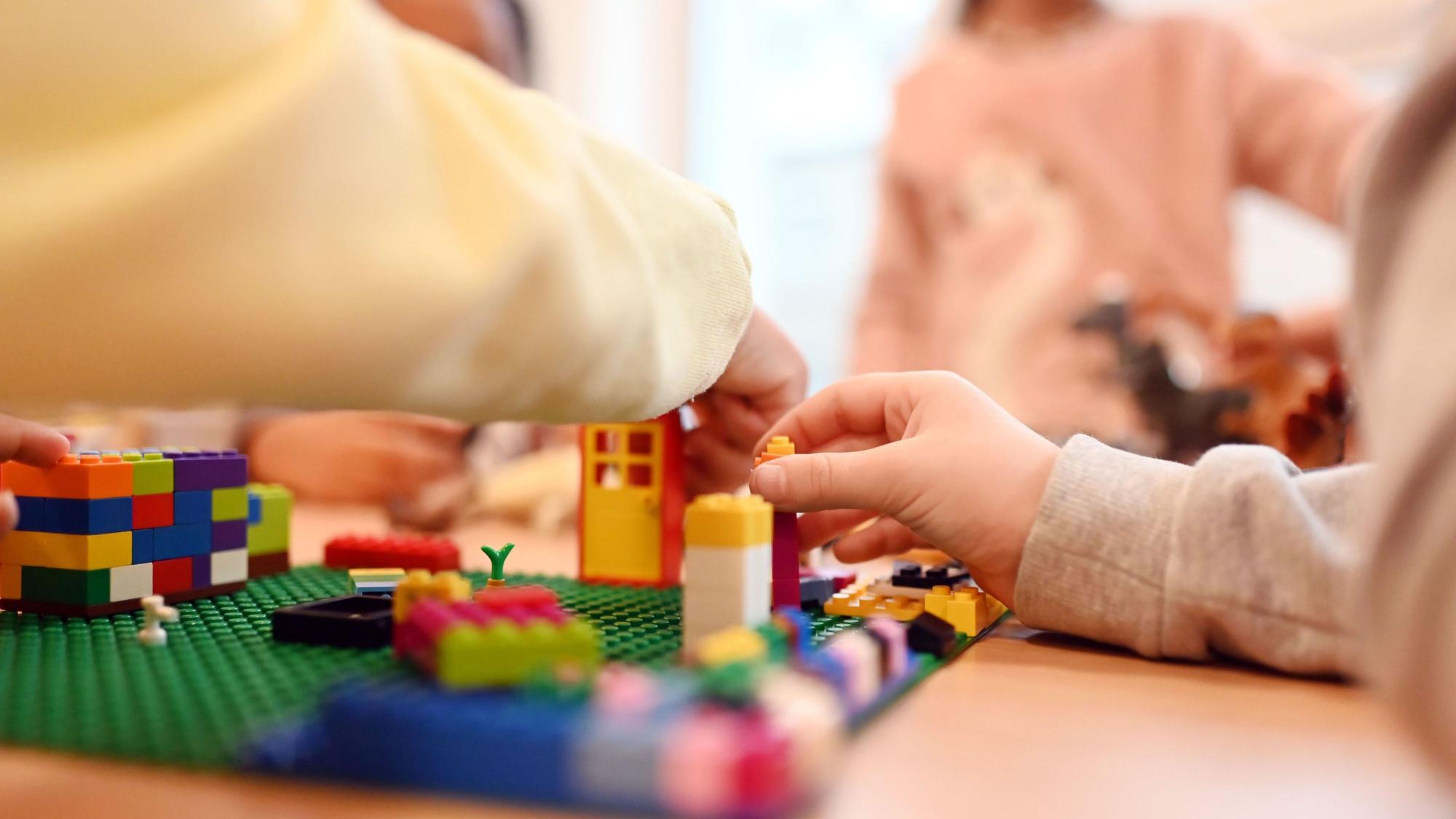Kinder spielen in einer Kita mit Legosteinen.